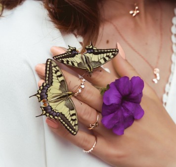 Purple Butterflies Sitting A Woman's Hand Holding A Flower